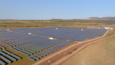 Aerial-side-pan-of-giant-solar-plant-on-aride-plain,-sunny-day