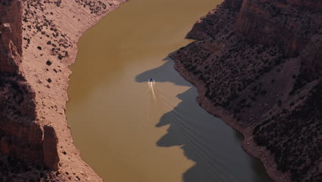 aerial view of a boat on a river flowing through a canyon