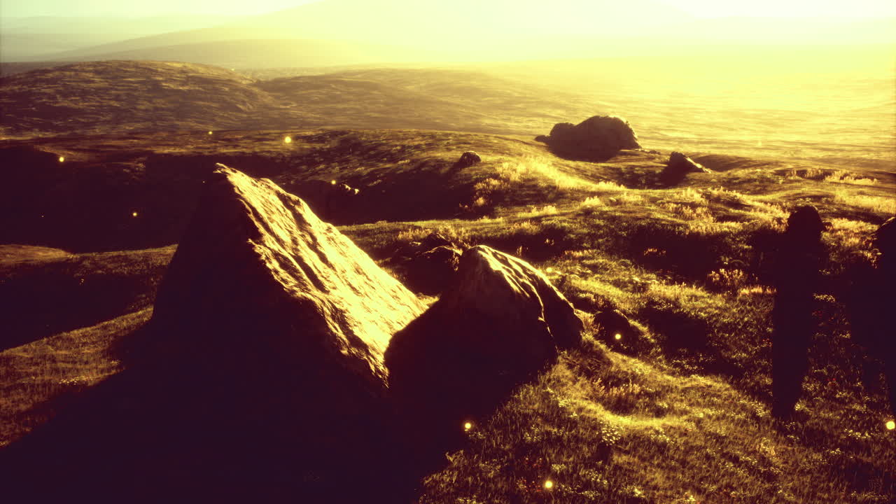 Scenic view of sunlit hills and distant landscape during golden hour