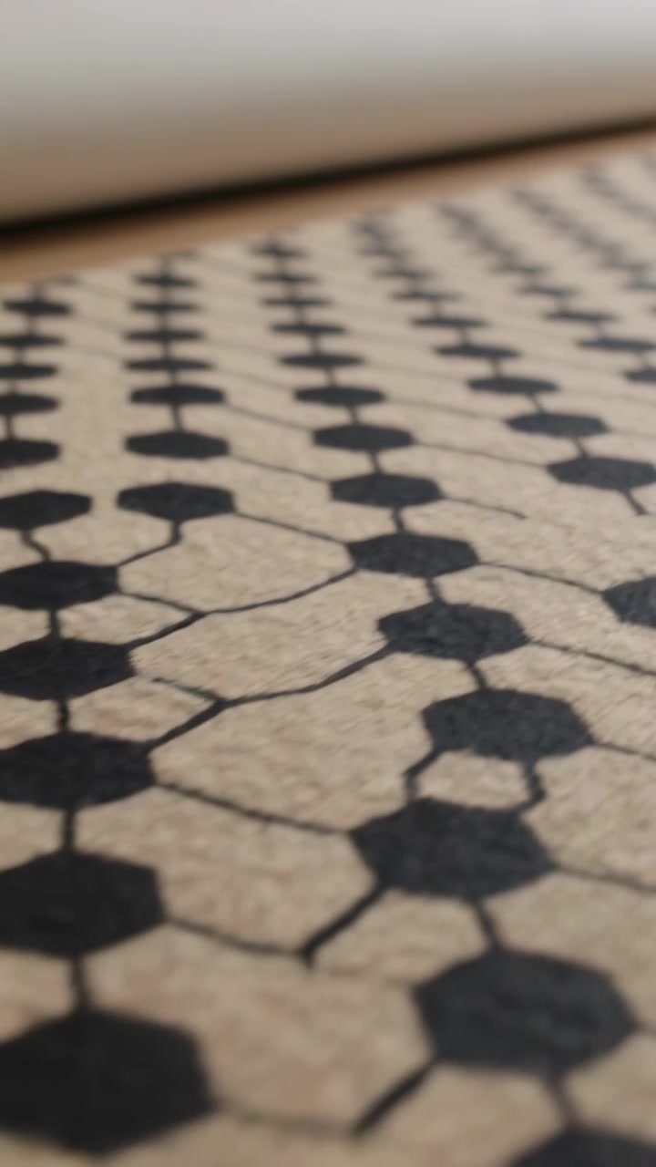 Vertical video: Shifting camera focusing on black hexagons on beige rug at home