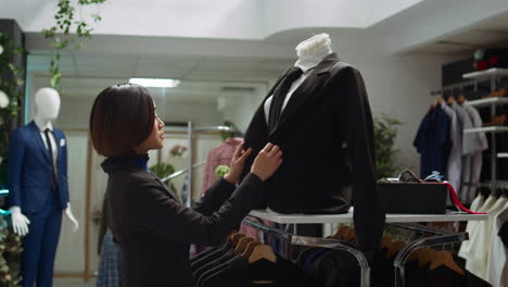 mujer comprobando un traje en un maniquí en una tienda de ropa