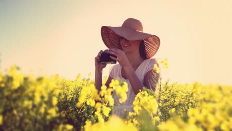 Mujer-Tomando-Fotografías-De-La-Cámara-En-El-Campo-De-Mostaza.