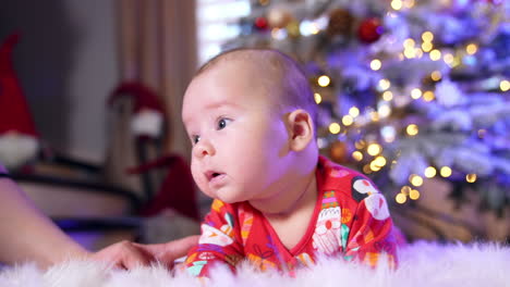 beautiful caucasian baby lies on the floor. little boy is trying to hold his head and mommy supports the child.