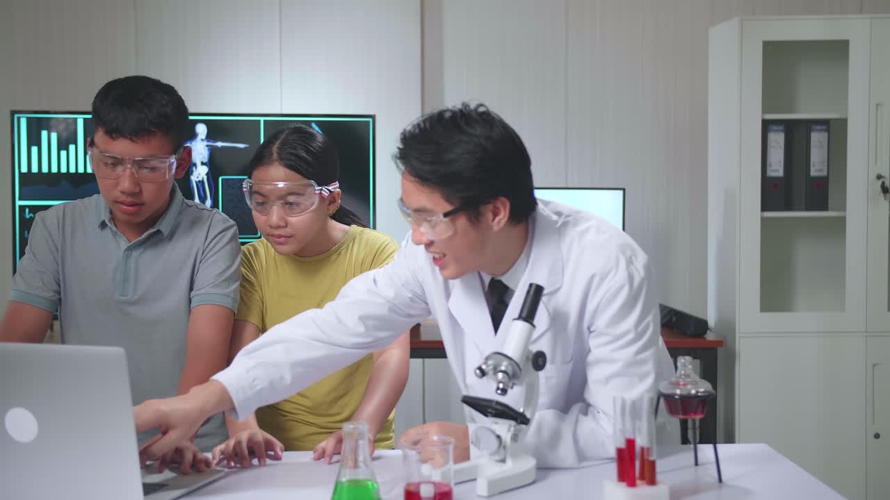 Young Asian Boy And Girl Learning Science Experiment In Laboratory With Teacher In Classroom, Teacher Explain With Laptop Computer