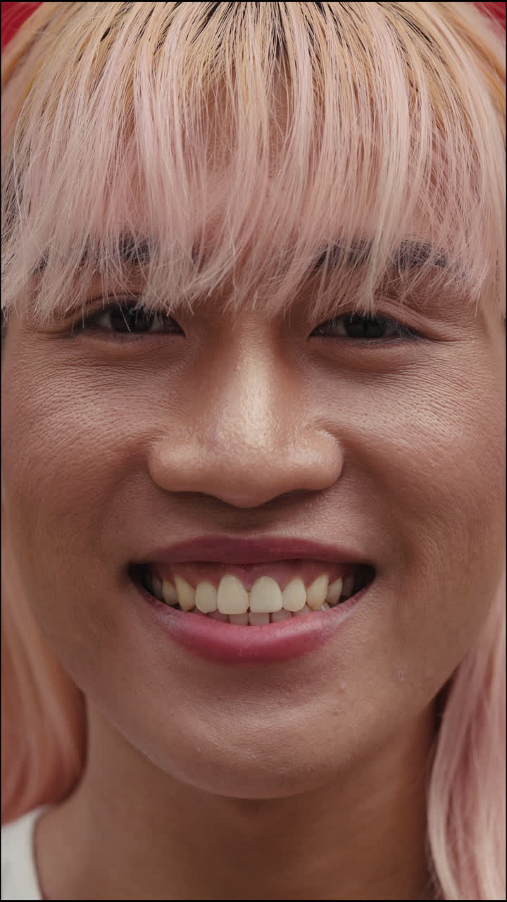 Close-up portrait of a smiling woman with pink hair