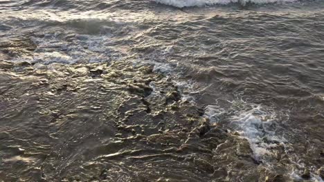 ocean waves reaching a rocky shore line on the beach