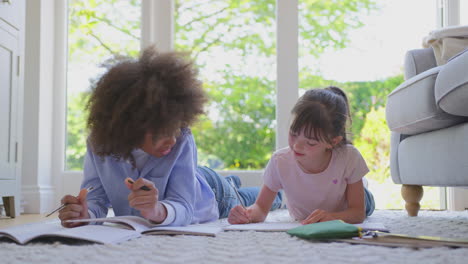 niño y niña acostados en la alfombra en el salón en casa haciendo la tarea escolar juntos