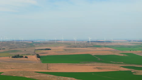 drone aerial shot of wind turbines in the background and brown, green fields around, slow motion, copy space