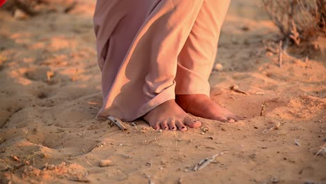 an arab lady stands barefoot in the soft sands of the arabian desert