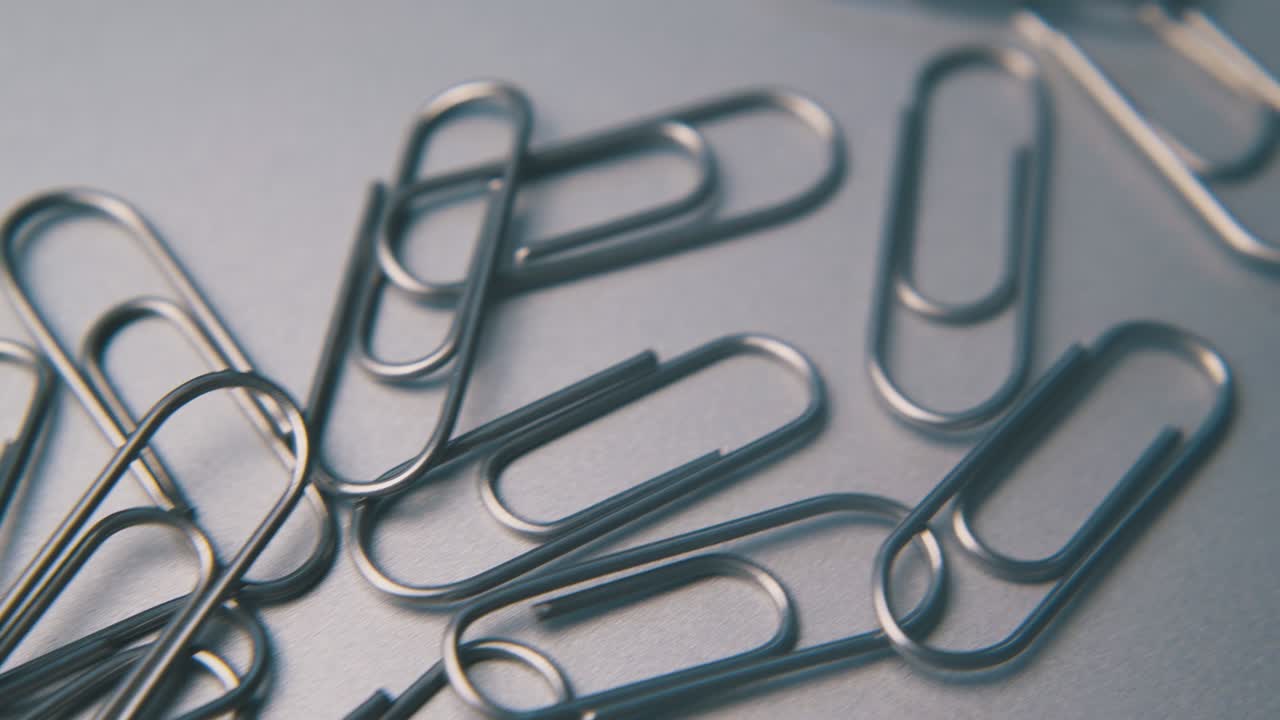 motion past heap of shiny paperclips on grey surface