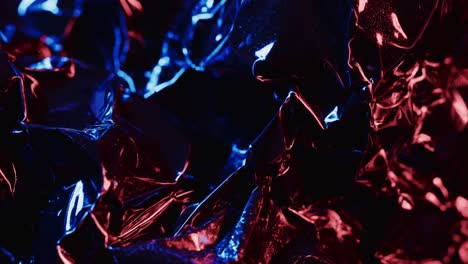 Close-up-of-blue-and-red-crumpled-pieces-of-plastic-material-in-slow-motion