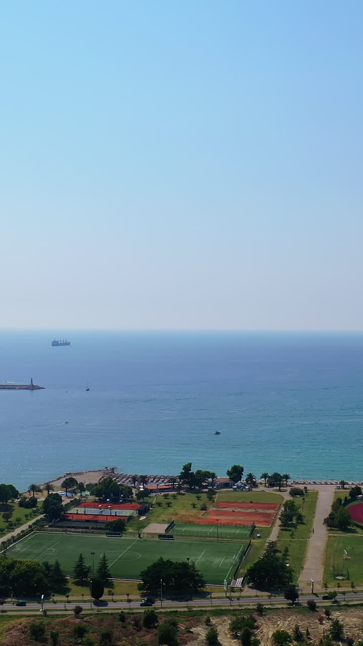 Busy seashore in the resort city of Bar, Montenegro. Beautiful cityscape and sea with yacht docks on sunny day. Top view. Vertical video