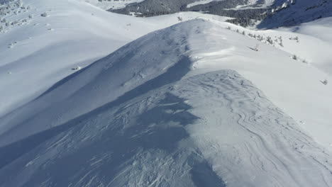 Vista-Aérea-Volando-A-Lo-Largo-De-Una-Cresta-De-Montaña-Cubierta-De-Nieve,-Para-Luego-Revelar-Los-Valles-De-Megeve-Y-Chamonix-En-La-Distancia