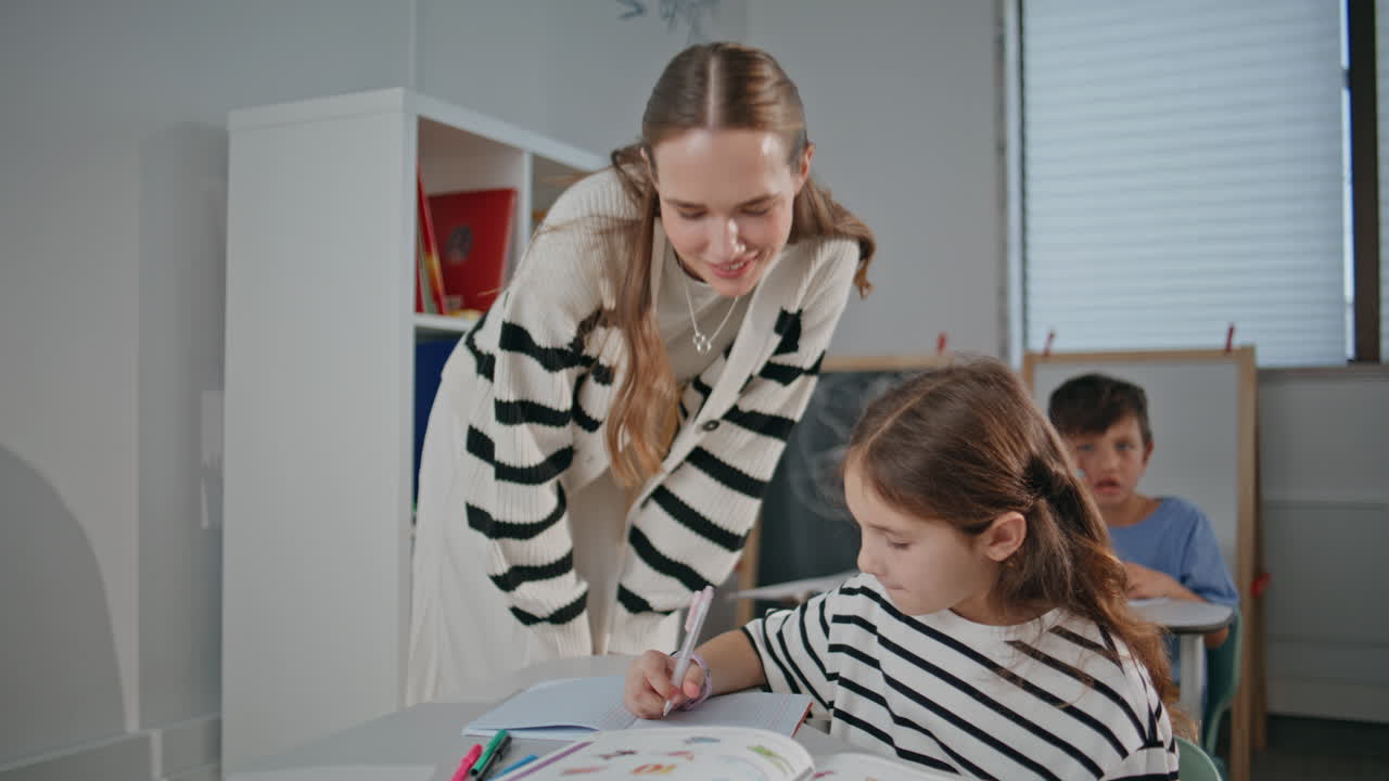 Woman teacher helping girl at lesson in classroom closeup. Lady talking student