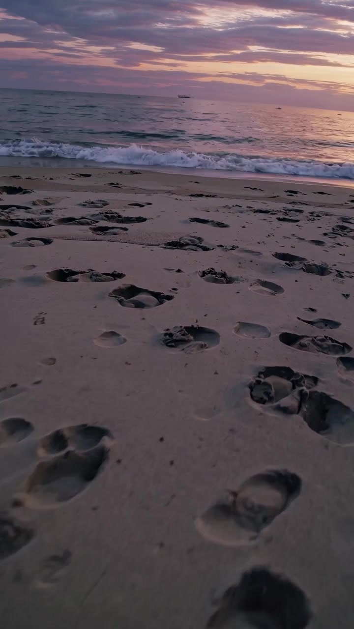 Impronte di piedi su Sandy Beach al tramonto