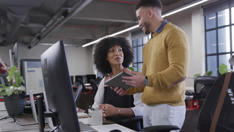 Diverse-male-and-female-colleagues-looking-at-tablet,-talking-and-smiling,-slow-motion