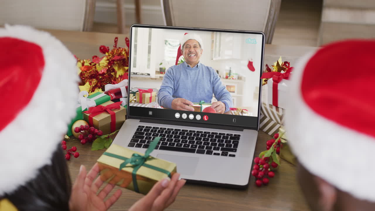 animación de una pareja diversa con sombreros de santa en una llamada de video portátil con un hombre en navidad