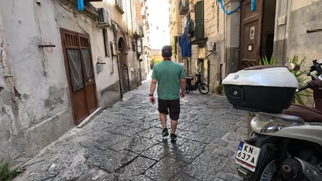 man walking down a narrow, cobblestone street