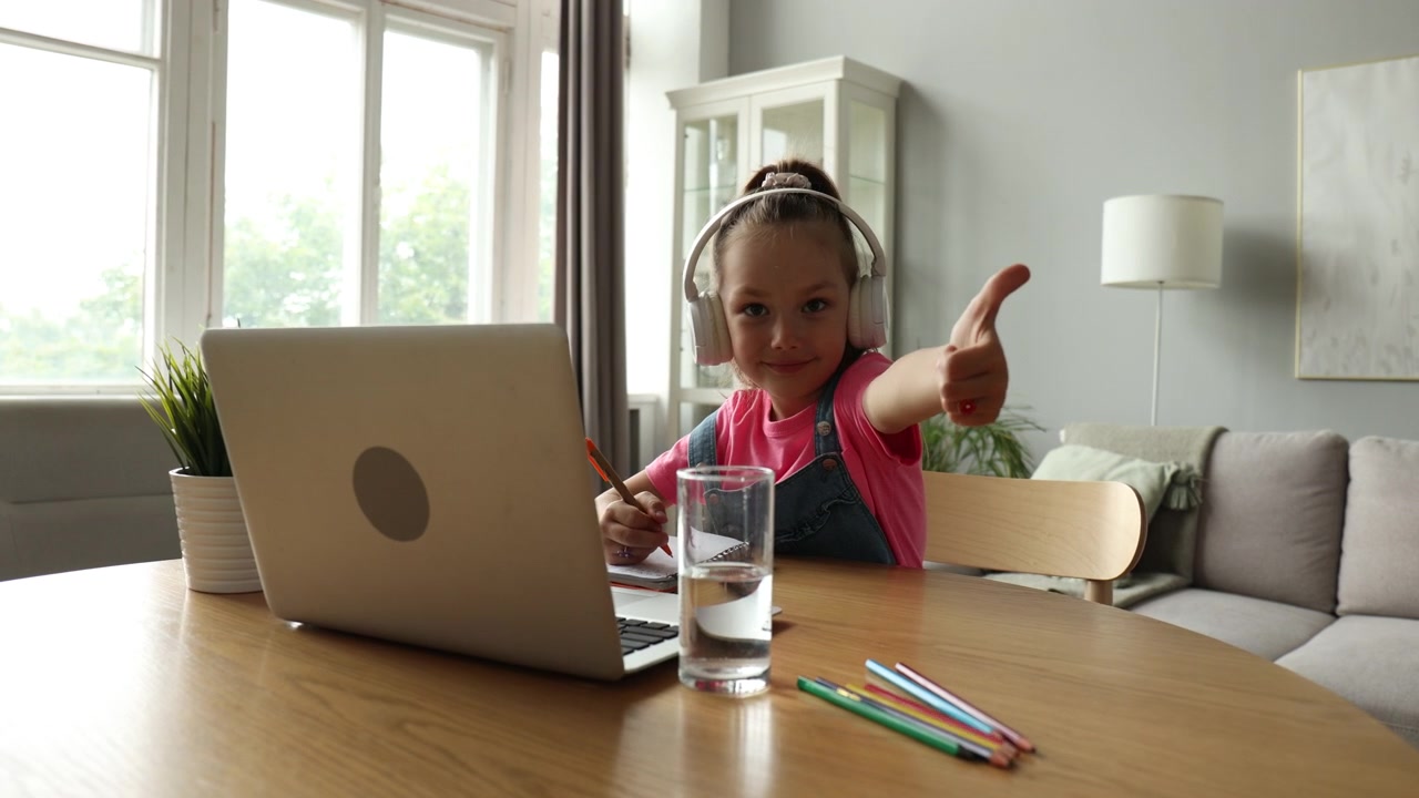Happy Young Girl with Headphones Learning Online and Giving Thumbs Up