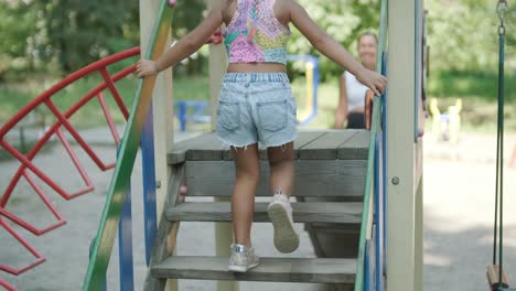 pregnant mother watching daughter play on slide at playground