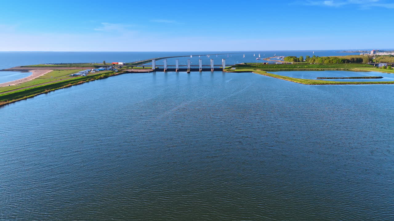 Netherlands sunset waterscape. Serene waters of the Netherlands reflect the vibrant colors of sunset, with bridges and sailboats enhancing the view