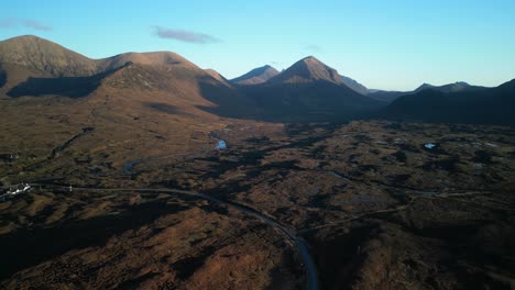 high altitude expansive shot of scottish moorland and highland road with red cuillin mountains at sunrise at sligachan on the isle of skye scotland