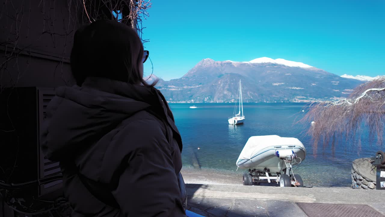 Woman sitting on the shadow near the shore of Lake Como in Varenna, Italy