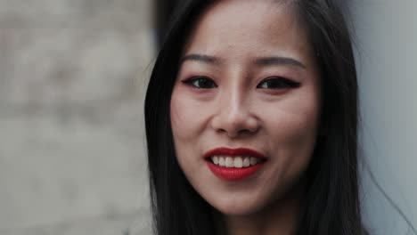 portrait of the face of charming smiled young girl with red lips while she standing outside