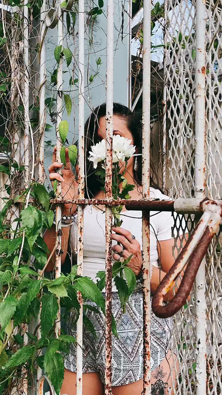 Woman Behind a Rusty Metal Fence with a Flower