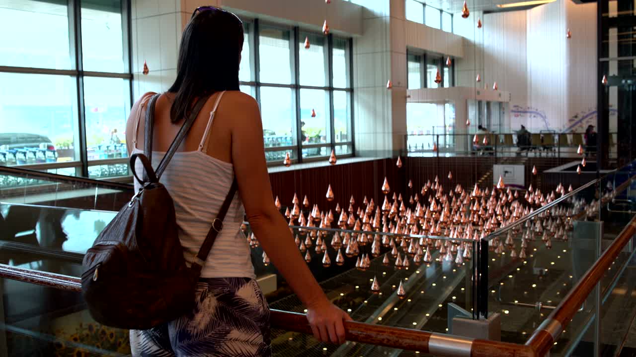 mujer mirando la lluvia cinética en el aeropuerto de singapur
