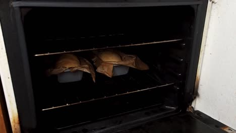 hands taking out loafs of bread out of the oven