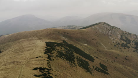 Ascending-aerial-shot-of-dry-peak-covered-with-little-greenery,-Slovakia