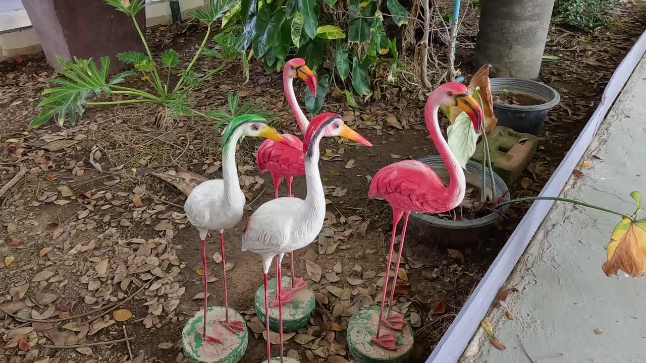 정원 식물 들 사이 에 서 있는 다채로운 플라밍고 동상 들