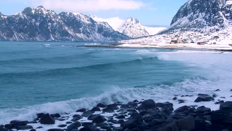 waves roll into a beautiful snow covered shoreline amidst fjords north of the arctic circle in lofoten islands norway 1