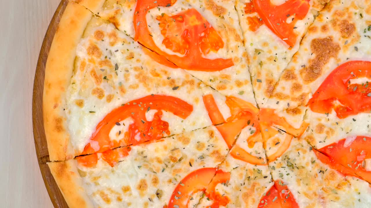 나무판 위에 토마토와 치즈를 넣은 피자를 절단하는 절반.