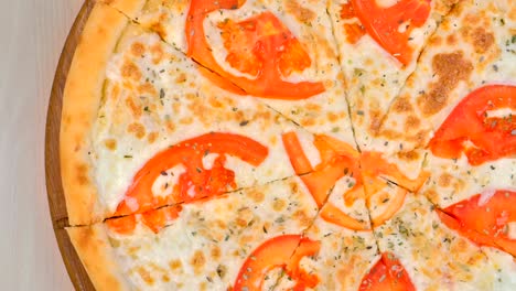 la mitad de cortar pizza con tomates y queso en una tabla de madera.