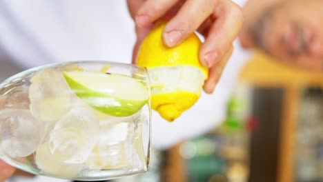 clip vertical de un barman preparando un gin tonic cepillando el limón alrededor del borde del vaso para darle un toque cítrico