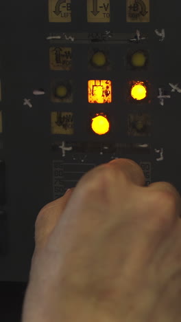 close-up of a hand operating an industrial control panel with glowing buttons