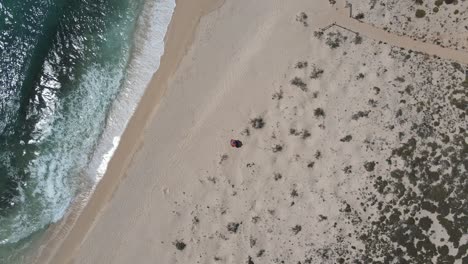 Antenne-Von-Oben-Nach-Unten-Von-Einer-Person,-Die-Am-Einsamen-Sandstrand-In-Australien,-Exmouth,-Liegt