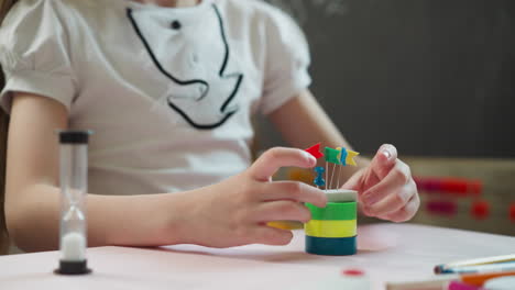 little schoolgirl puts eraser with tag pins on rings at desk