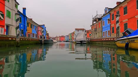 unusual and different low angle panoramic view of burano colorful houses seen from canal center, italy