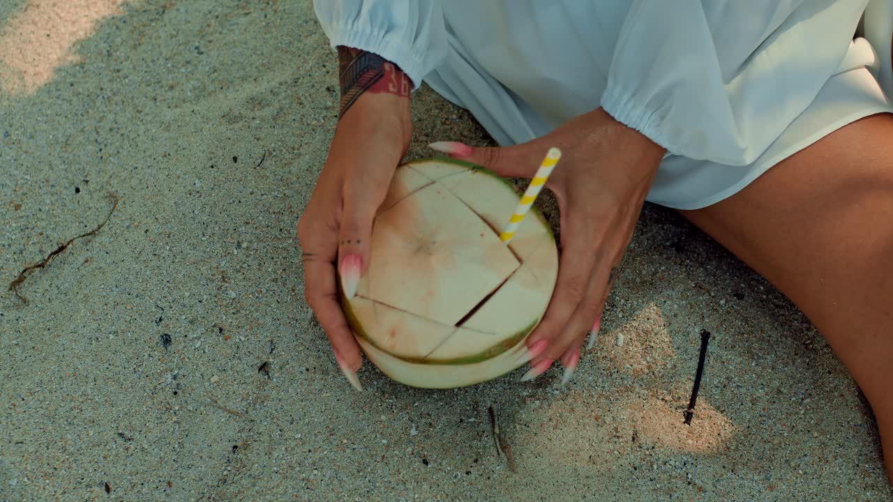 женщина пьет кокосовую воду на пляже