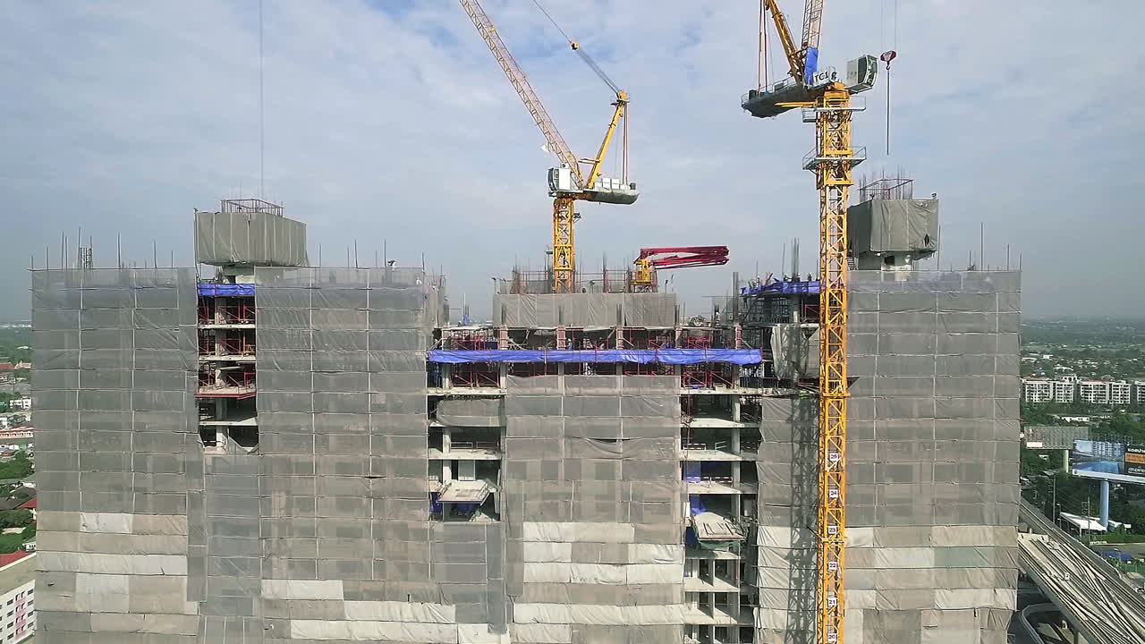 vista aérea de un moderno edificio de gran altura en construcción en el ajetreado distrito de negocios del centro de la ciudad con trabajadores, andamios y grúas