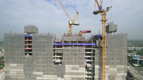 Aerial-view-of-modern-high-rise-building-under-construction-in-the-busy-city-centre-business-district-with-workers,-scaffolding-and-crane