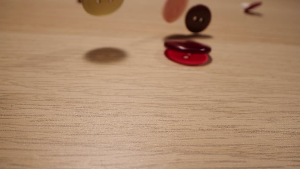 primer plano de diferentes botones de costura de colores que caen en una mesa de madera. concepto de moda