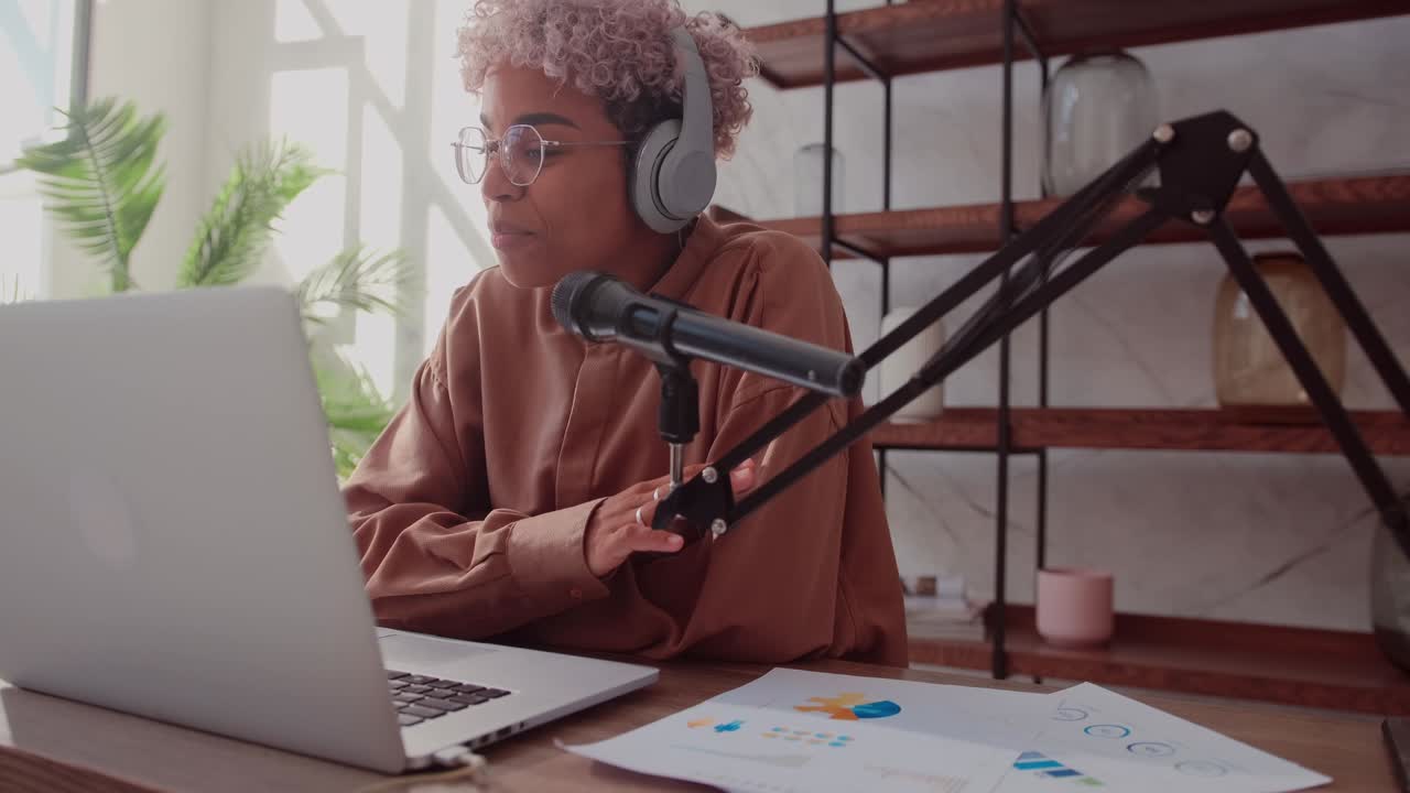 Woman with microphone and headphones talking and recording podcast at studio