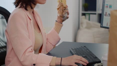 executive manager having takeaway meal order eating tasty sandwich during lunchtime