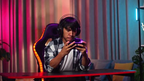 un adolescente asiático serio jugando videojuegos en su teléfono inteligente.