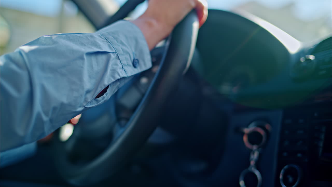 Close-up of a person rotating the steering wheel while driving the car in daylight