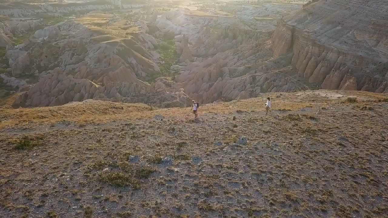 orbita aérea con destello de lente: excursionistas en el sendero del borde del cañón de hoodoos